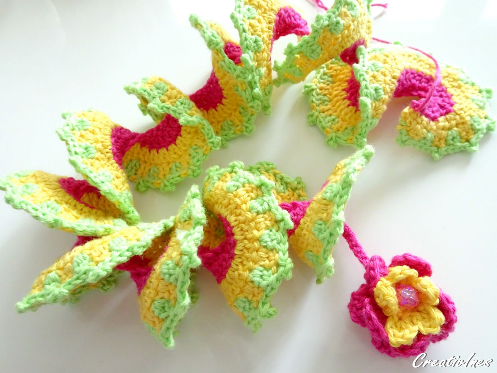 Gehäkelte Windspirale mit Blume, Farben pink, gelb und hellgrün.