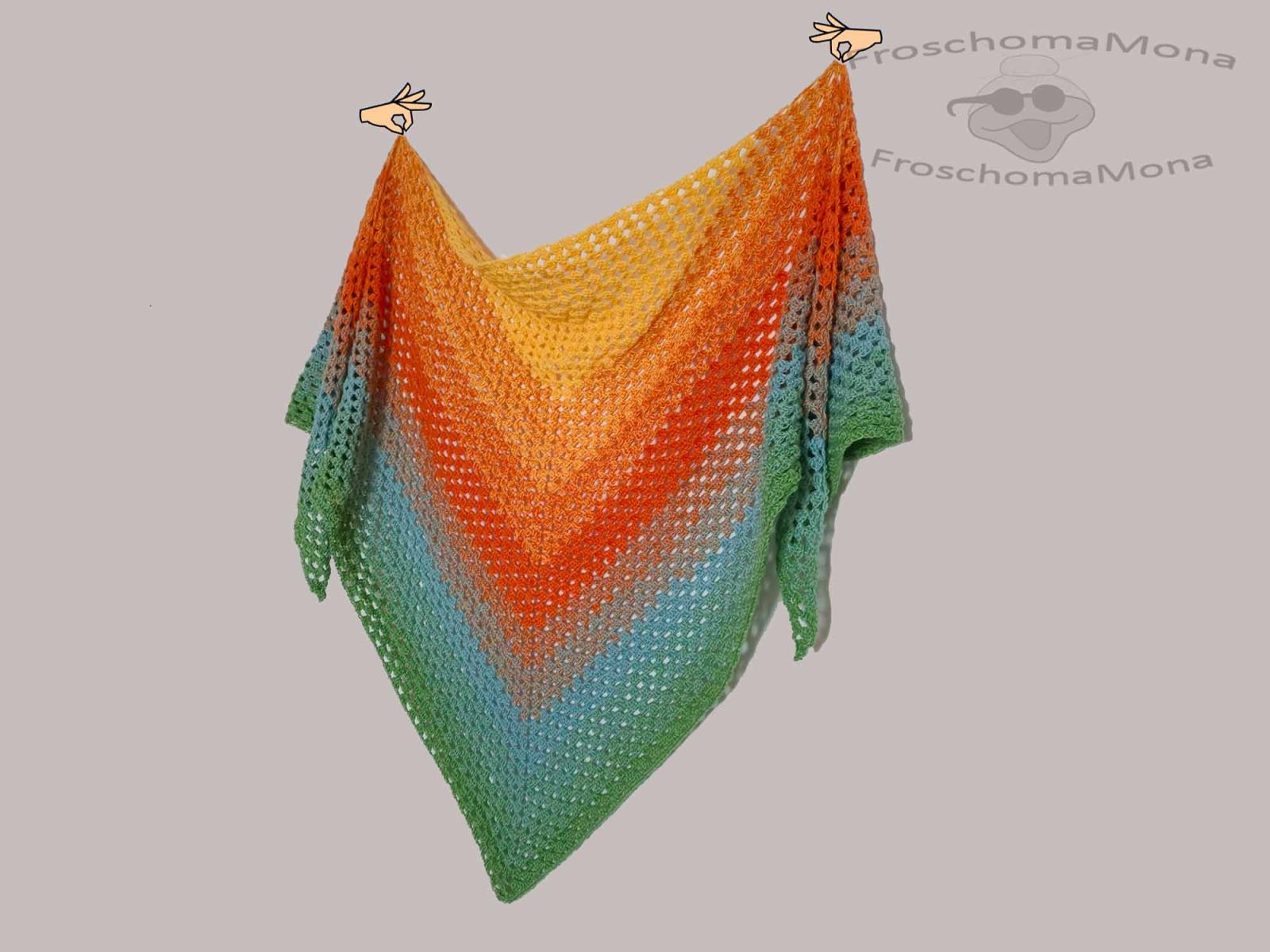 Das gehäkelte Tuch wird von zwei Comic-Händen hochgehoben und gehalten.