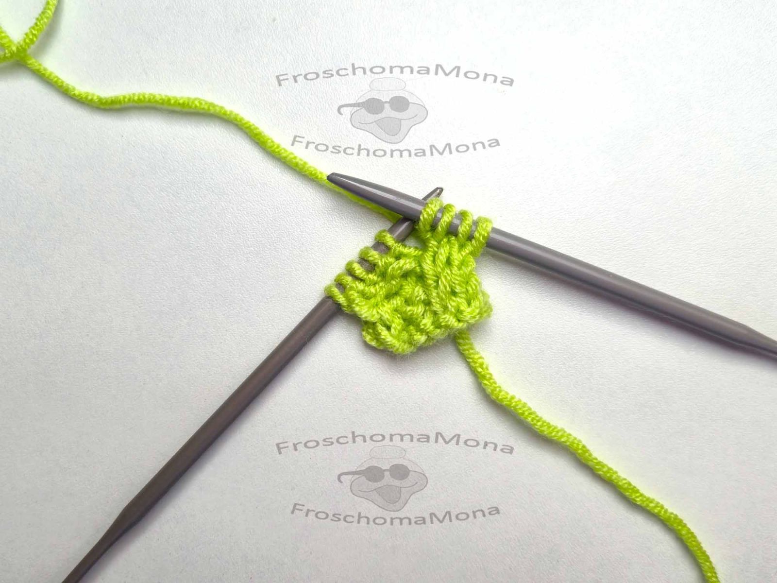 Das grüne Strickstück zeigt nun die nächste Zunahme und es sind nun 9 Maschen vorhanden.