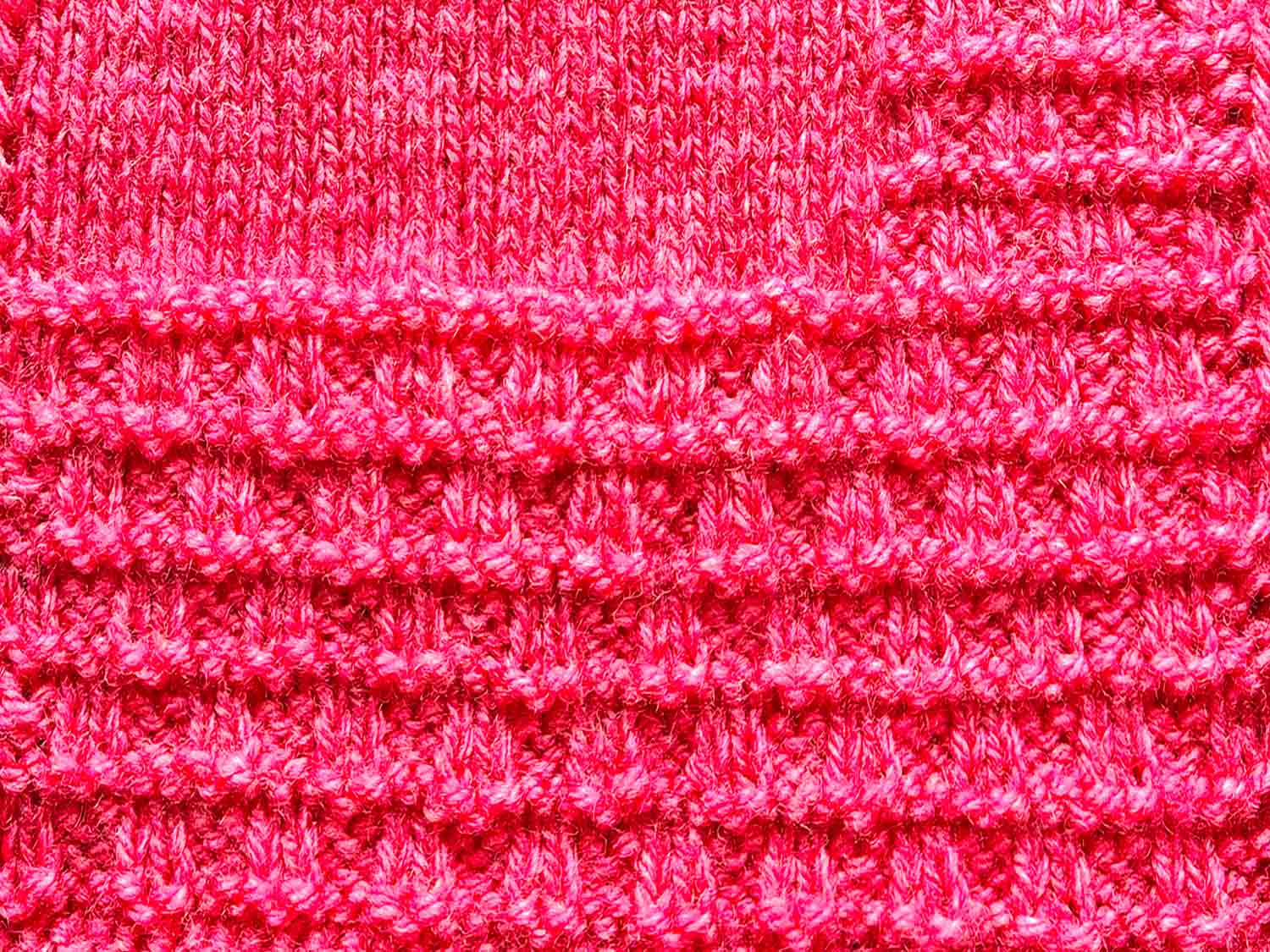 Mit rotem Garn gestrickt wurde ein karierter Rand mit waagerechten Streifen.