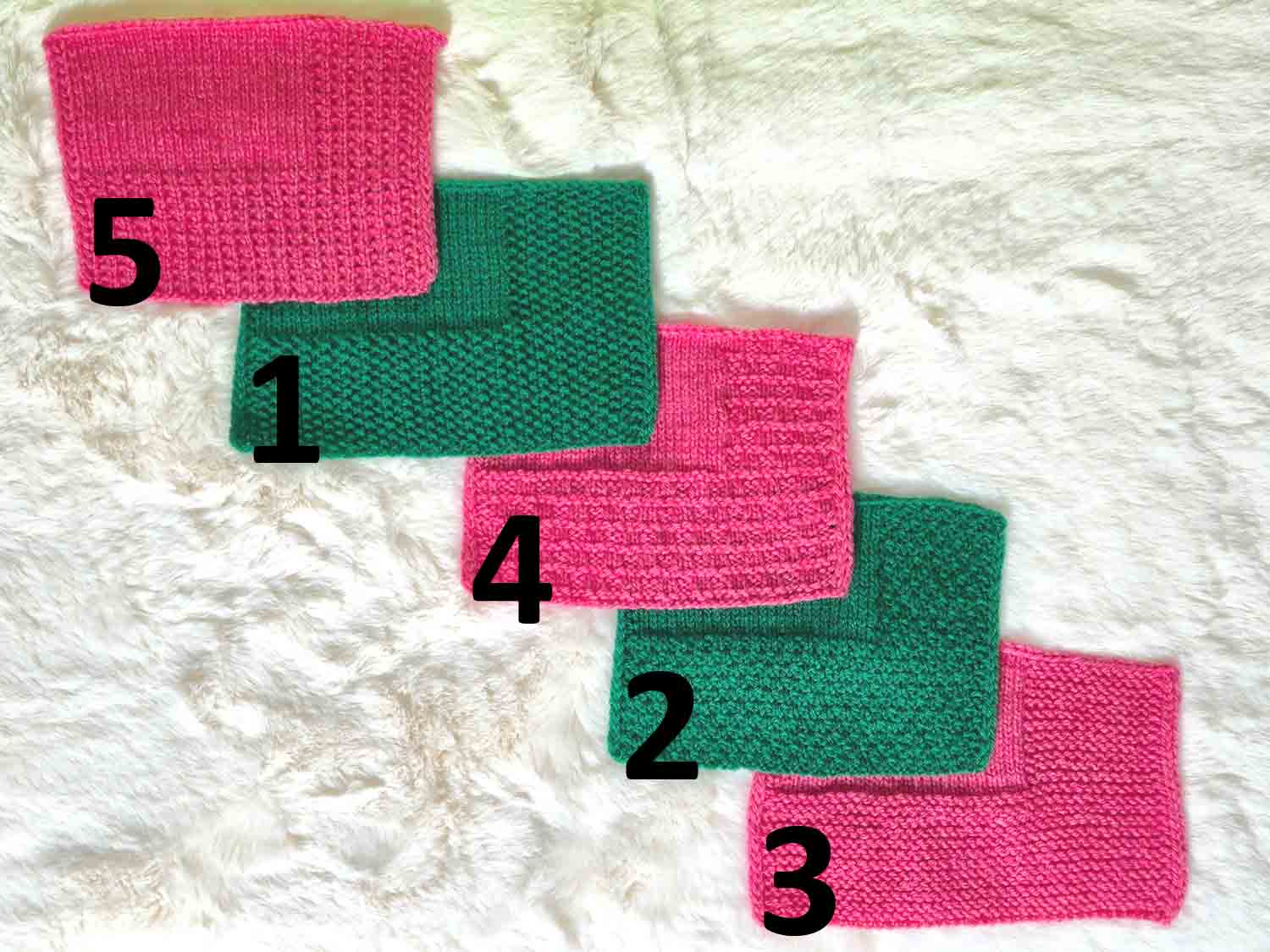 fünf verschiedene gestrickte Deckenränder in grün und rot liegen auf einem Fell.