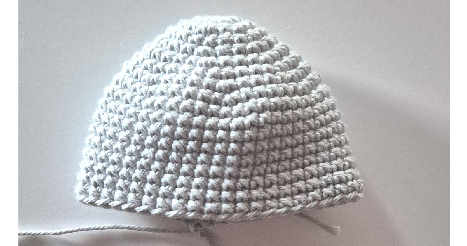 Das gehäkelte Stück des Eierwärmers ist mittig gefaltet. Der Endfaden liegt unten mittig.