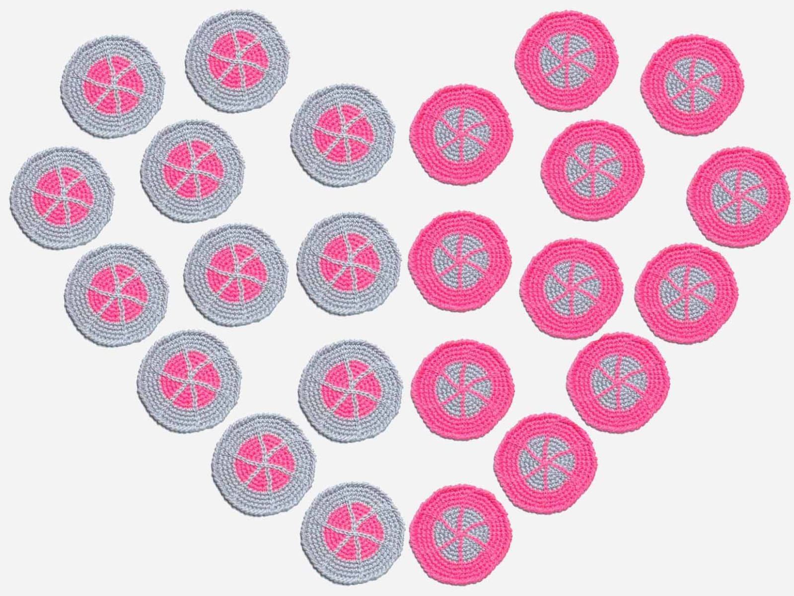 24 gehäkelte Untersetzer in pink und grau wurden als Herz auf eine helle Unterlage gelegt.