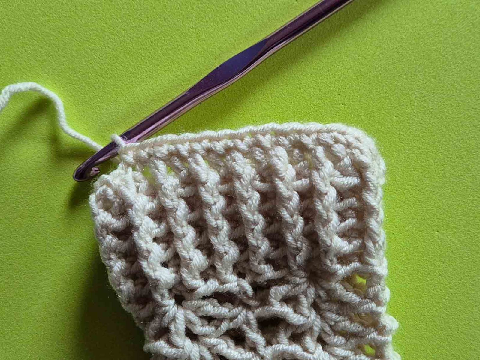 Das Bild zeigt das Umhäkeln der Handstulpe an der Seite des Armbündchens.