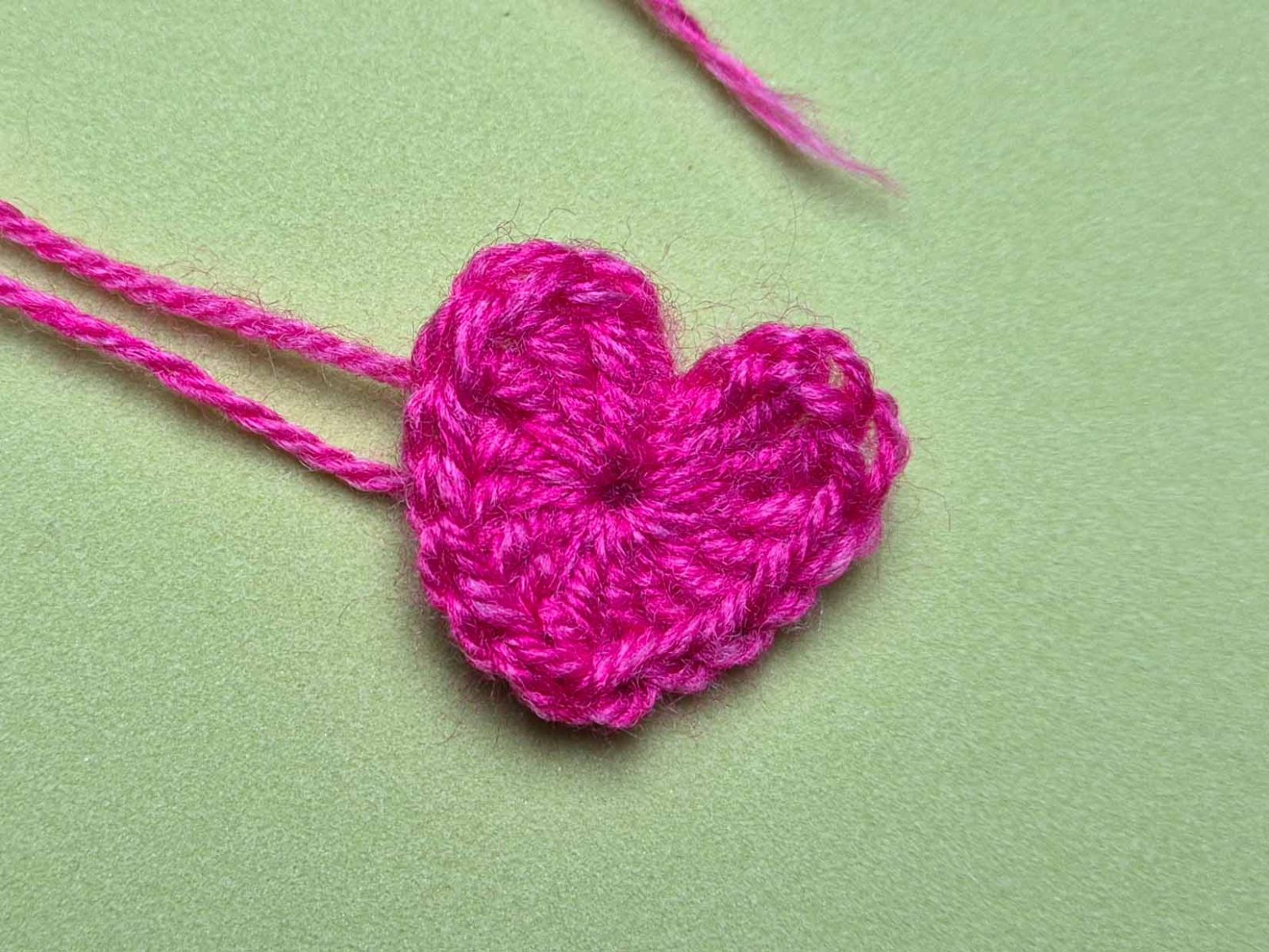 Ein Herz in pink liegt auf einem grünen Untergrund.