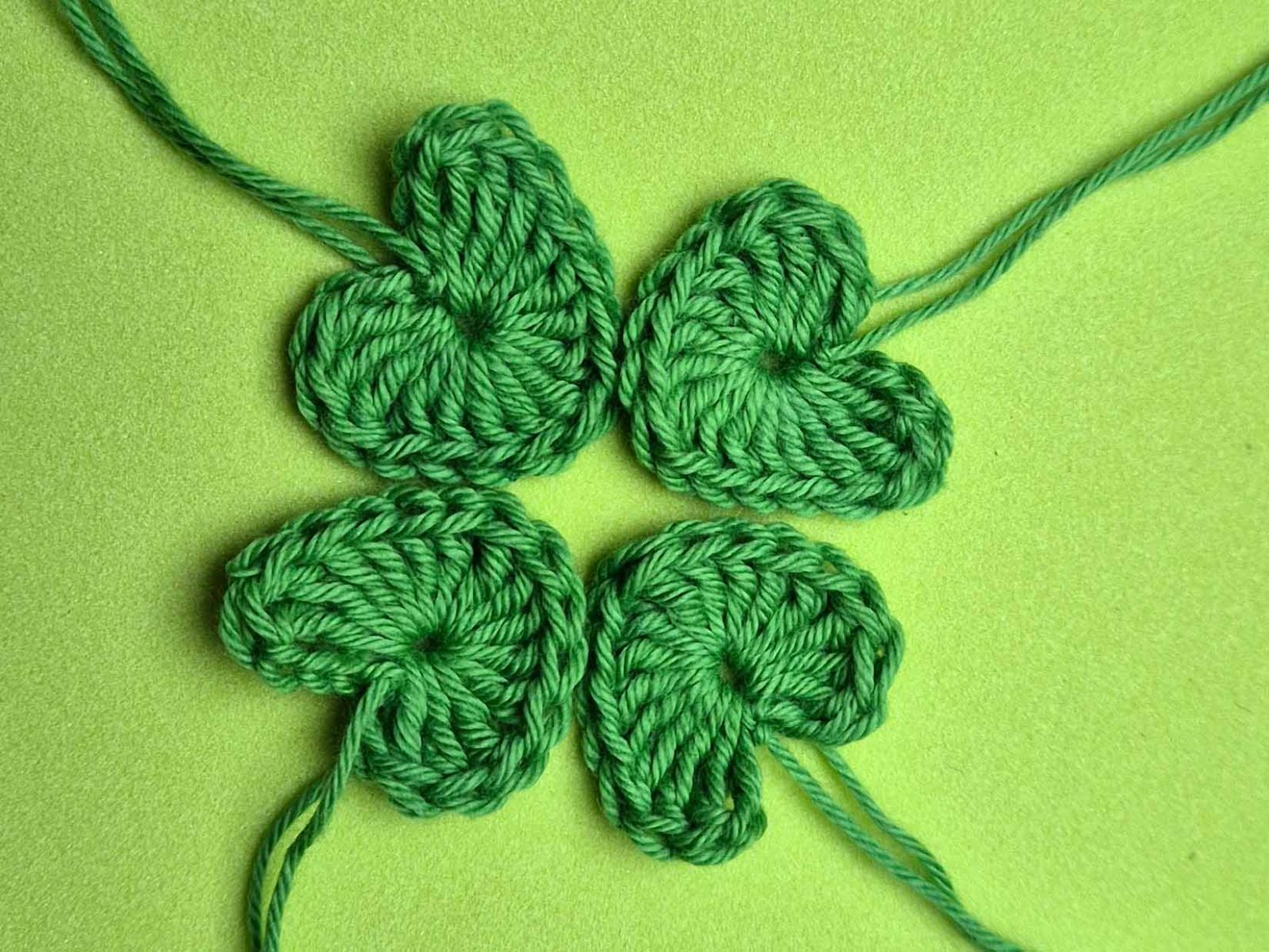 Vier gehäkelte Herzen wurden zu einem Vielkleeblatt gelegt.