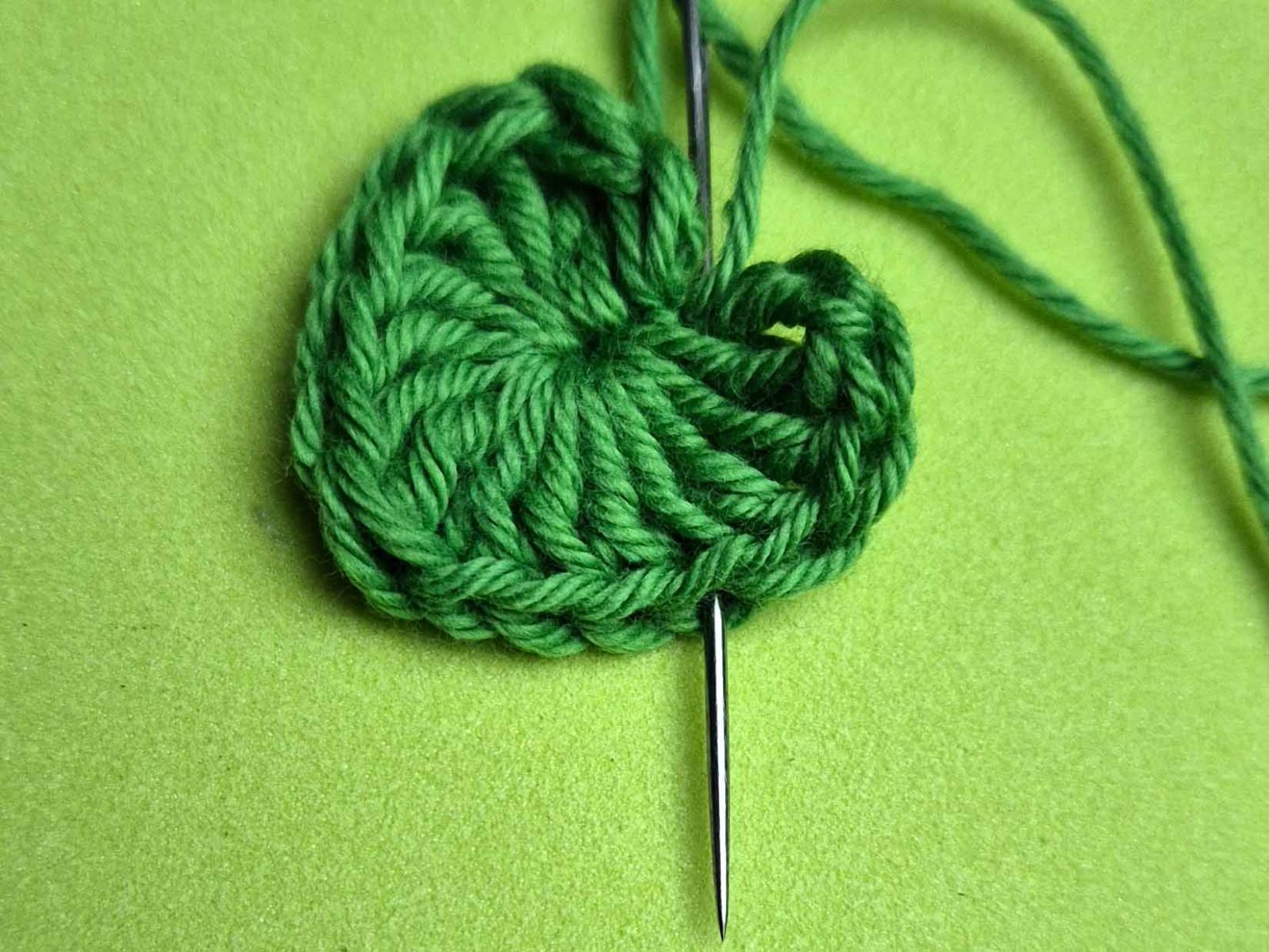 Die Nadel taucht zwischen zwei Maschengliedern wieder auf und an dieser Stelle werden zwei Herzen miteinander verbunden.