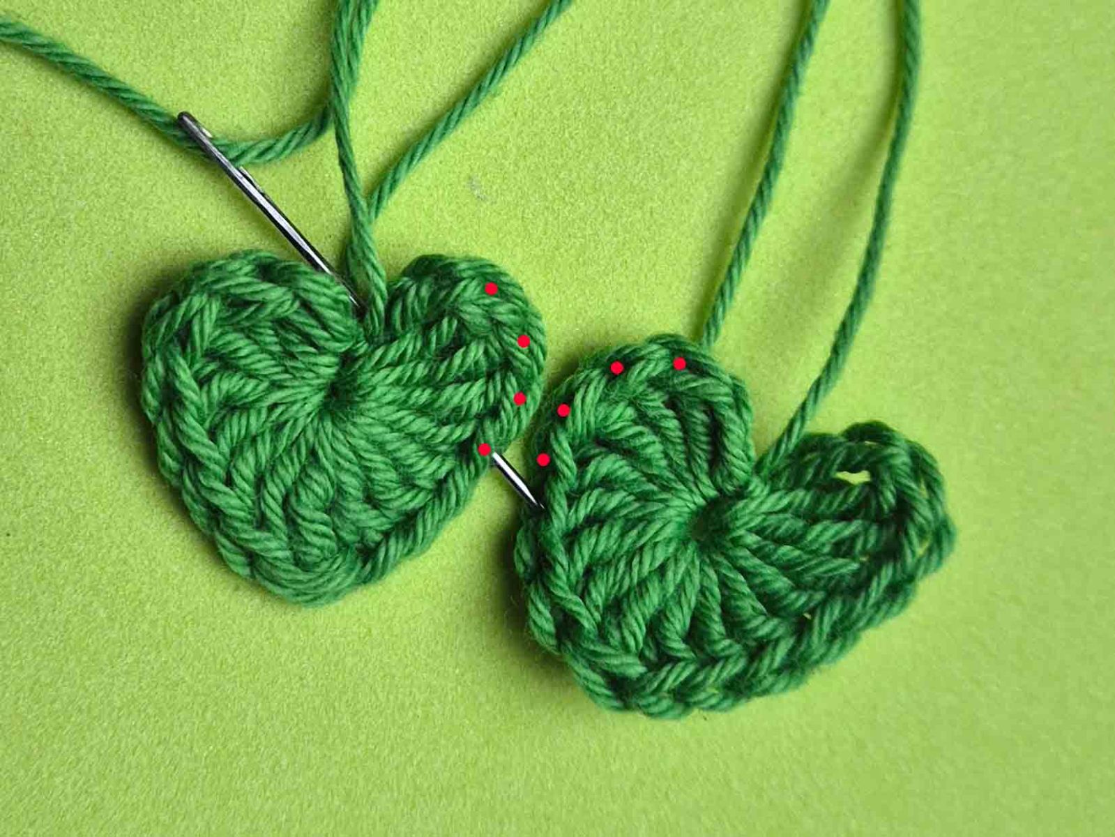 Zwei gehäkelte Herzen sind zu sehen, bei denen mit roten Punkten die Maschen gekennzeichnet sind zum Zusammennähen.