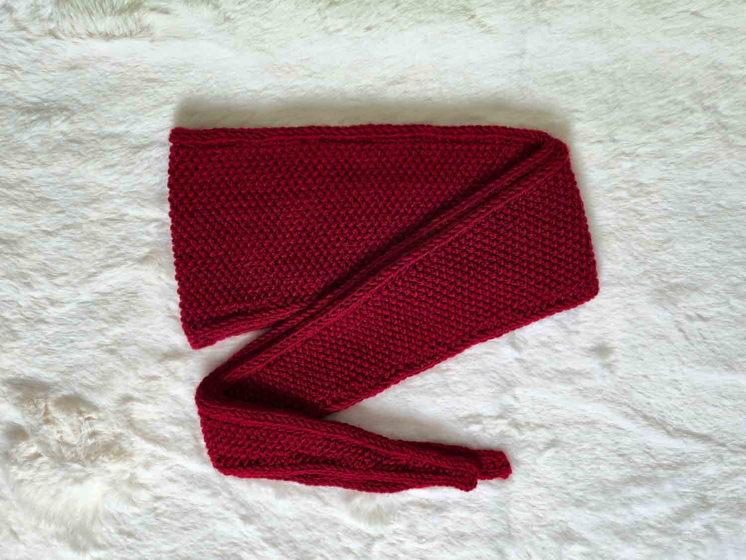 Ein rotes Tuch im Zick-Zack zusammengelegt liegt auf einem hellen Fell.