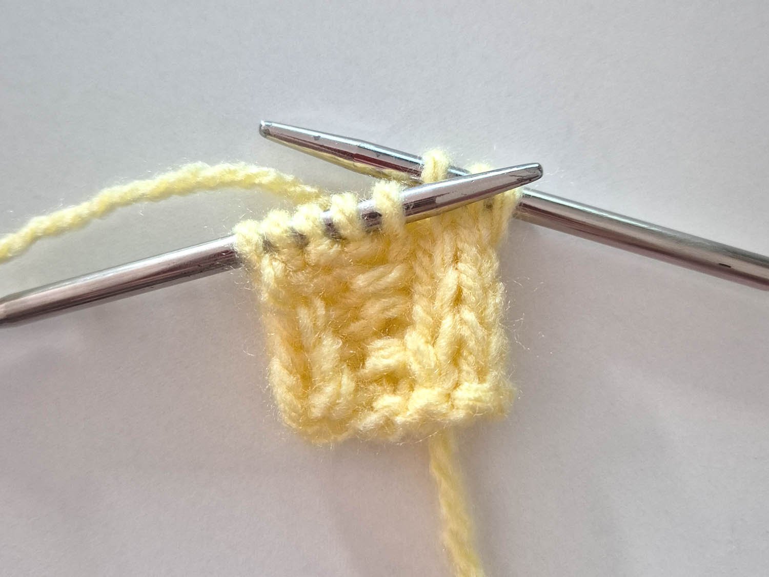 In gelber Wolle wurde die erste Zunahme gearbeitet.