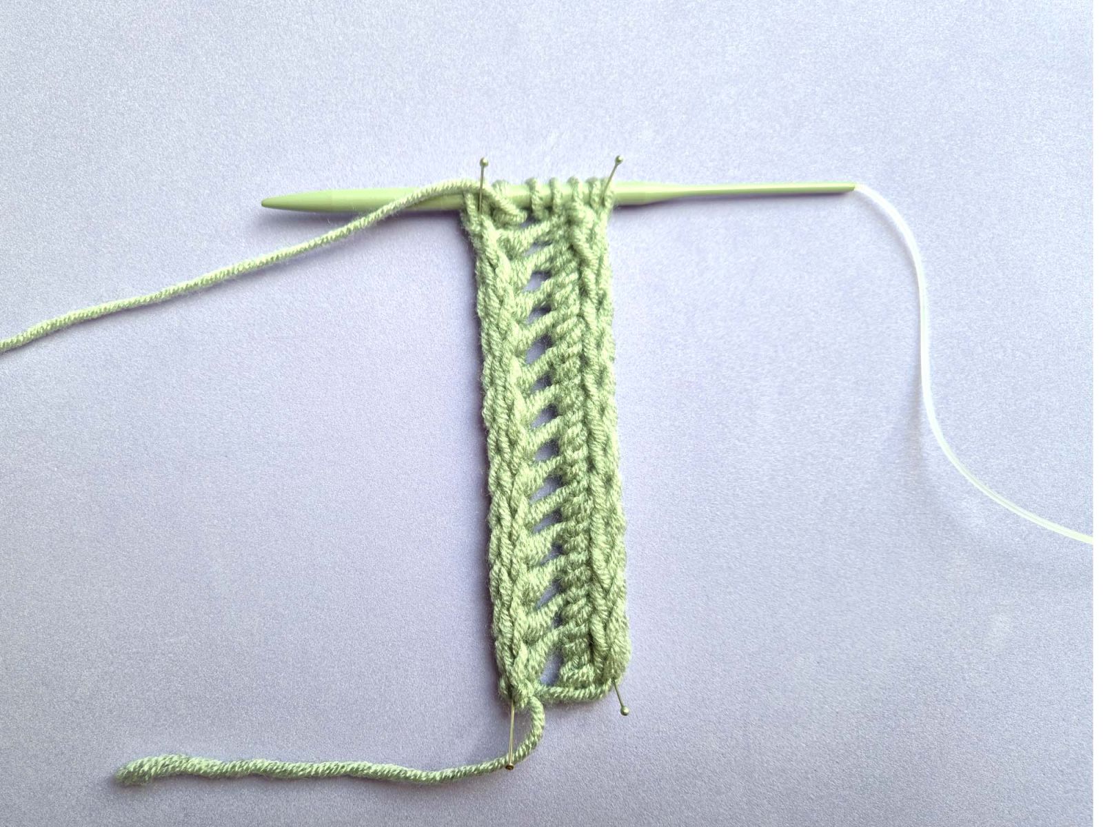 Das Strickstück zeigt 14 Löcher übereinander.