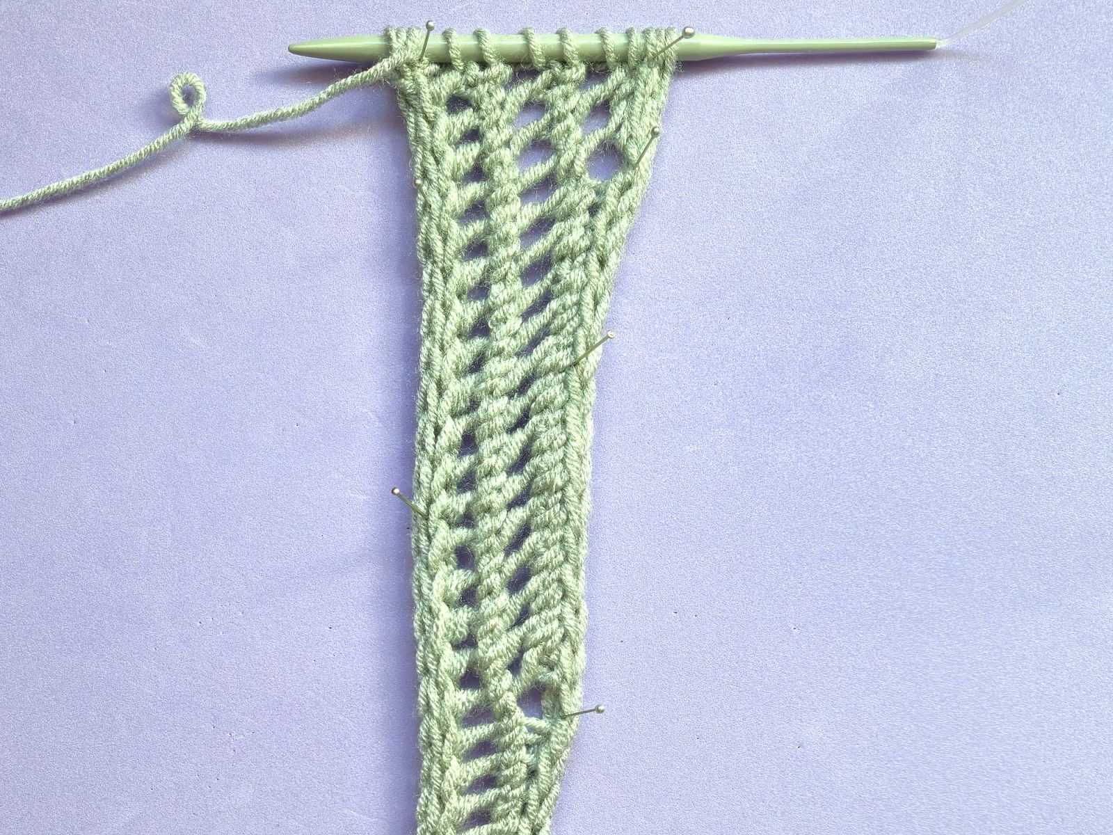 Das Strickstück von der Vorderseite aus gesehen nach Reihe 64. Die 3. Lochreihe ist jetzt bereits mit 3 Löchern sichtbar.