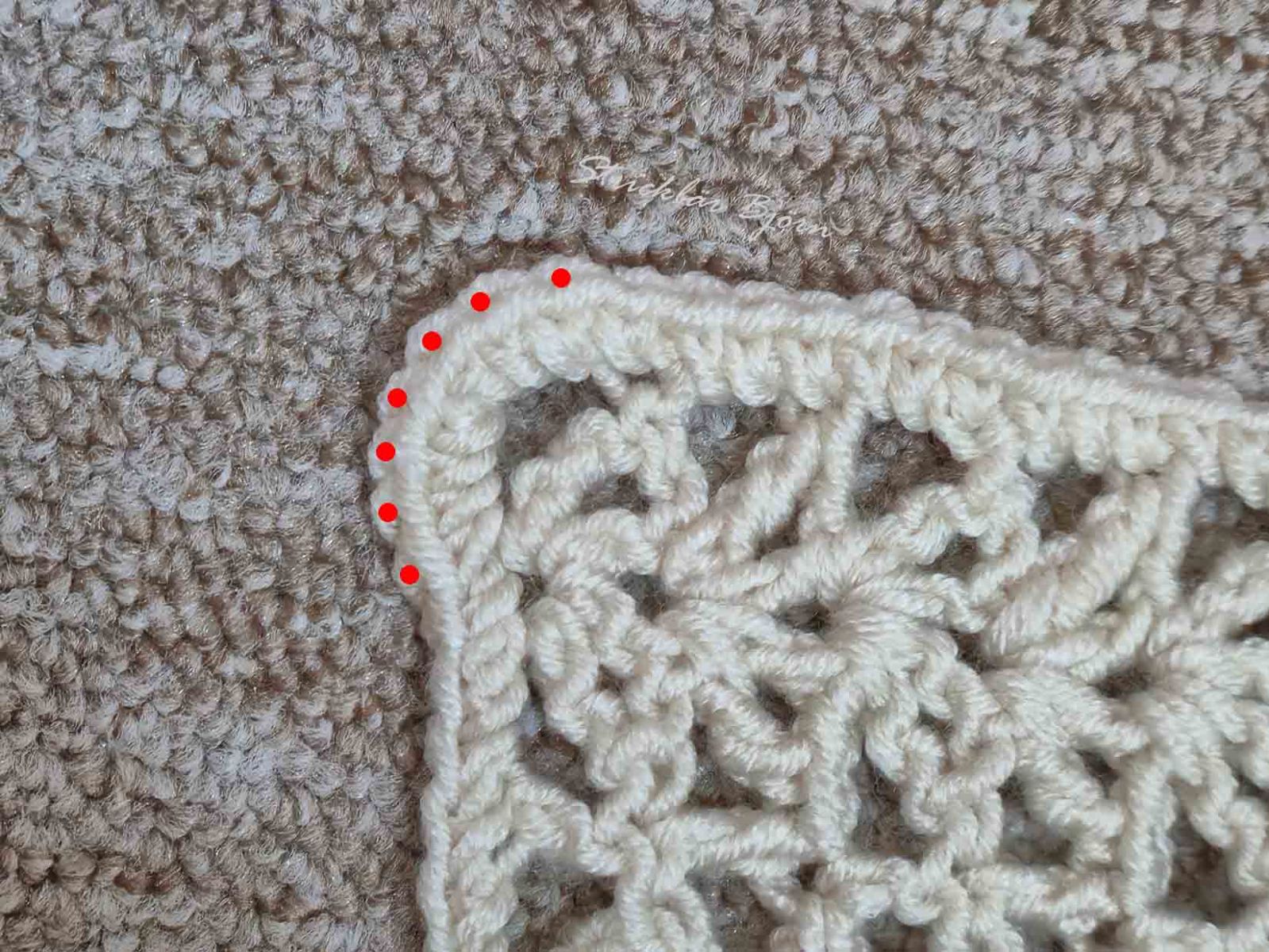 Das Bild zeigt die umhäkelte Ecke des Häkelstücks. Die Eckmaschen wurde durch rote Punkte gekennzeichnet.