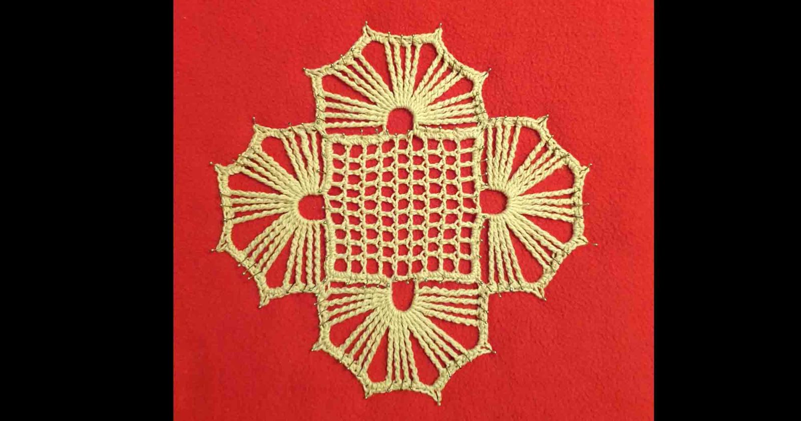 Das gehäkelte Deckchen wurde auf einer roten Unterlage gespannt.