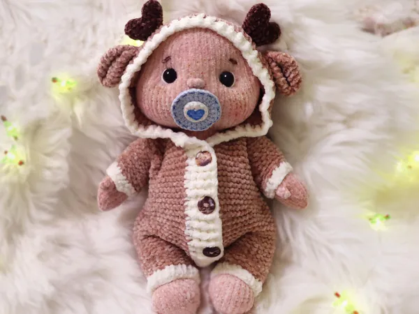 A fluffy little baby in a cozy deer, knitted.