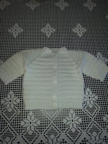 Eine hübsche kleine Strickjacke mit Raglanärmel für ein Neugeborenes.