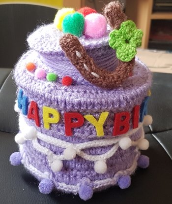 Das ist gehäkelt und gebastelt. Sieht kompliziert aus. Ist aber machbar. Habe eine größere Dose mit Deckel ausrangiert.
Ich wollte das noch eine Kleinigkeit herein passt.
Die Buchstaben sind aus Filz.
Die lustigen Pompoms hergestellt.
Kordel um die Torte gehäkelt und wo gewünscht Pompoms anbringen