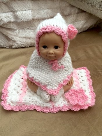 Das ist ein Püppchen von einer Nachbarin. Die Kleine war komplett nackt. Ich weiß nicht mehr, wie groß sie ist und das Besondere an ihr ist, dass Arme und Beine fest am Körper sind, so dass wirklich nur so ein Poncho möglich war. Ein Unterhöschen hat sie auch an, das war sehr schwierig anzubringen. Eine lange Hose war nicht möglich, so blieb mir nur die Möglichkeit, ihr Söckchen anzuziehen und sie auf eine warme Decke zu setzen. Ich finde das Püppchen reizend und die Nachbarin ist fast ausgeflippt vor Freude.