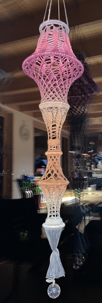 Häkelmuster nach Anleitung, mit wenigen zusätzlichen Elementen, in neuer Zusammenstellung an einem Stück gehäkelt. Von oben nach unten mit Farbverlaufsgarn „pro Lana“ , 1-2-3 Ideen, Farbe 09, Lauflänge 100g/315m, Häkelnadel 2,5. Der Zottel unten braucht recht viel Garn, so dass vom 100gr-Knäuel nicht mehr viel übrig bleibt.
Ohne Zottel und Aufhängung etwa 65cm lang.