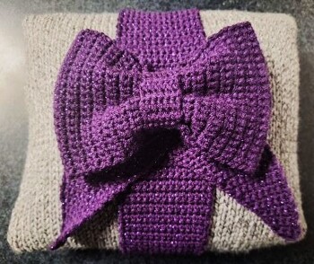#Kissen mit Schleife. Schleife mit lila- Glitzer Garn gehäkelt. Kissen mit melliertem Grau glatt rechts gestrickt. Anleitung ist ausführlich und verständlich. Danke:-)