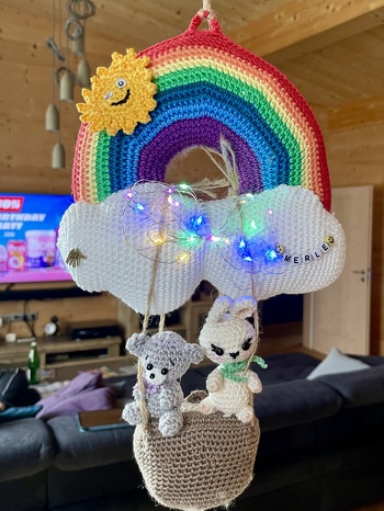 Da ich Wolle mit weniger Lauflänge genommen habe, hat die Spieluhr nicht mehr reingepasst. Somit habe ich die Wolke und den Regenbogen als Ballon genutzt und die Spieluhr in einen Korb darunter verstaut und gleich 2 Passagiere mit integriert.😉