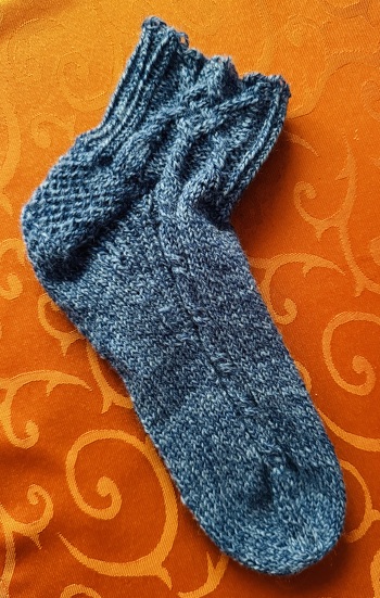 Ich habe eine Socke fertig gestrickt, anprobiert und festgestellt, dass der Schaft viel zu kurz ist und dadurch
runterrutscht- für mich sehr unbequem. Daher habe ich den Schaft verlängert (neu gestrickt) bis Rd 26. Dabei strickte ich nur den Zopf (Chart A) in die Maschen 9,10,11,12. Die anderen blieben 4 re. Maschen.
Jetzt passt die Socke und gefällt mir super.