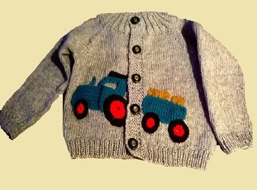 Gestrickte graue Kinderjacke mit blauer Traktor- und Anhänger-Applikation auf der Vorderseite