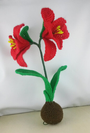 Gehäkelte rote Zwiebelblume mit zwei Blüten, grünen Blättern und brauner Zwiebelbasis