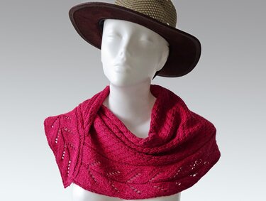 Schaufensterpuppe mit gestricktem fuchsiafarbenem Loop‑Schal und Blatt‑Ajourmuster