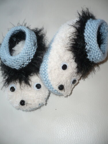 Gestrickte Babyschuhe weiß-blau mit schwarzem Flauschrand und beweglichen Wackelaugen
