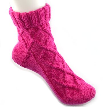 Pinke gestrickte knöchellange Damensocke mit Zopfmuster auf weißem Hintergrund