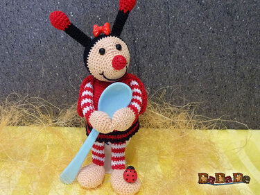 Gehäkelter Marienkäfer-Eierwärmer mit rotem Bogen, blauem Löffel und roten Antennen