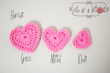 Drei rosa gehäkelte Herzen in verschiedenen Größen auf hellem Hintergrund