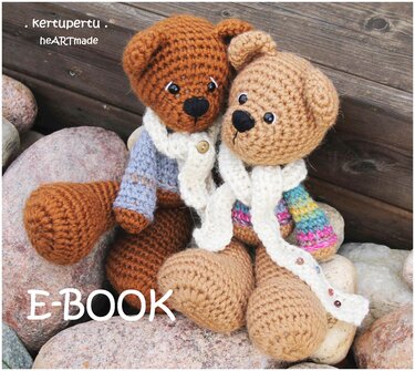 Zwei gehäkelte Amigurumi-Teddybären mit Schals auf Steinen vor Holz