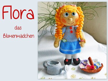 Gehäkelte Amigurumi-Puppe mit gelben Locken, blauem Kleid, Blumenkorb und Gießkanne