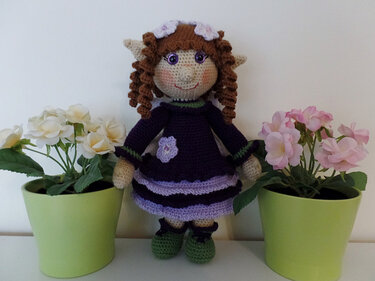Gehäkelte Amigurumi-Elfenpuppe mit braunen Locken, spitzen Ohren, lila Kleid und grünen Schuhen