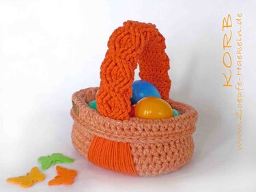 Gehäkelter Korb in Pfirsich- und Orangetönen mit bunten Ostereiern