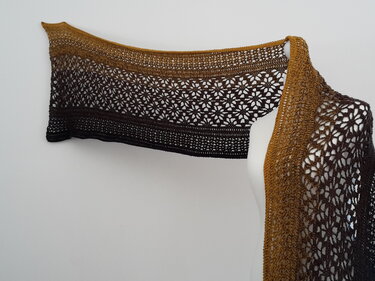 Langes gehäkeltes Tuch mit Lochblütenmuster und Senf‑bis‑Dunkelbraunem Farbverlauf an Schaufensterpuppe drapiert