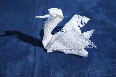 Weißer Schwan aus Spitze auf dunkelblauem Stoff