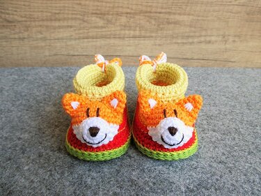 Paar gehäkelter Babyschuhe mit Fuchsgesichtern in Orange, Gelb, Rot und Grün