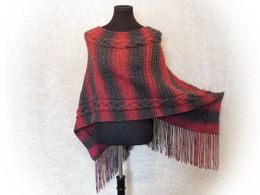 Black mannequin wearing a red and charcoal striped knitted poncho with cable band and long fringe