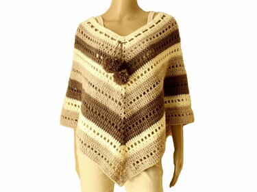 Mannequin trägt gehäkelten Poncho in Beige- und Brauntönen mit V‑Ausschnitt und Pompons