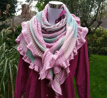 Mehrfarbiges gestricktes Dreieckstuch in Rosa, Lila und Mintgrün mit Rüschenkante auf einer Schaufensterpuppe
