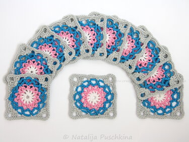Mehrere gehäkelte Granny Squares in Rosa, Blau und Grau auf weißem Hintergrund
