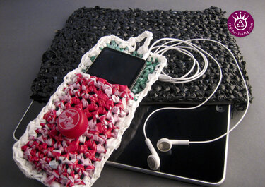 Nahaufnahme einer rot-weiß-grün gehäkelten Hülle aus Plastiktüten mit kleinem Gerät und roter Kappe, daneben eine schwarze Tasche und weiße Kopfhörer.