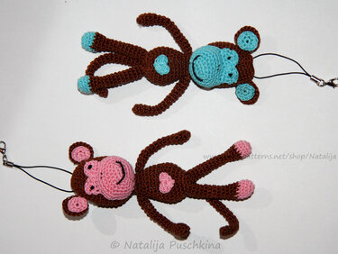 Zwei gehäkelte Amigurumi-Affen in Braun mit hellblauen bzw. rosa Details als Schlüsselanhänger