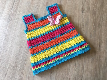 Ärmelloses mehrfarbiges gehäkeltes Babykleid mit gezacktem Saum und Schmetterling