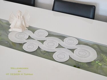 Gehäkelter weißer Tischläufer mit Wellen- und Kreisdesign auf modernem Esstisch mit Engelsfigur