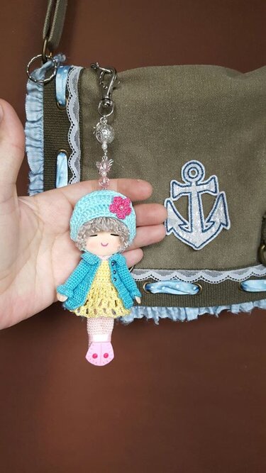 Mini-Amigurumi-Puppe als Schlüsselanhänger mit Perlenkette an Tasche