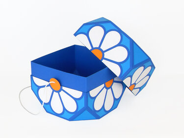 Blaue sechseckige Papier-Geschenkbox mit offenem Deckel, weiß-orangem Gänseblümchenmuster und elastischer Schlaufe